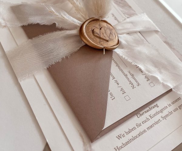 Papeterie-Serie Boho Glam, Hochzeitseinladung bestehend aus Einladungskarte, Detailskarte, RSVP-Karte, zusammengehalten von einem Seidenband mit Wachssiegel und Trockenblume.