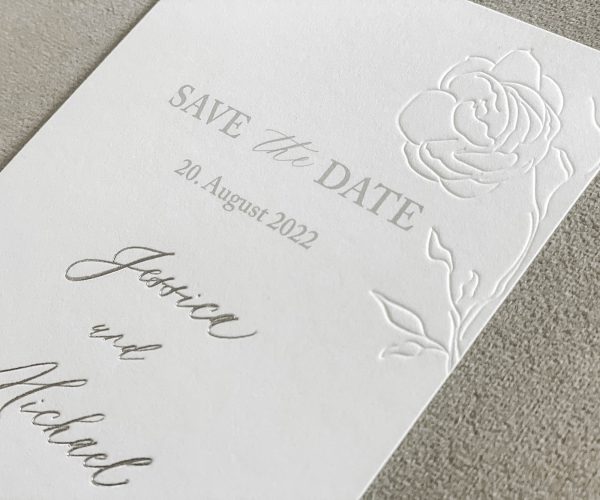 Papeterie-Serie Elegance, Save-The-Date-Karte aus dickem, weißen Papier mit Blindprägung und Silberprägung